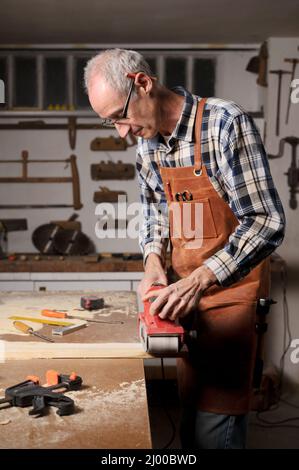 Carpenter sanding wood with belt sander at workshop in wooden board project or woodworking carpentry. High quality 4k footage Stock Photo