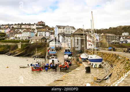New Quay, Ceredigion, Wales - March 2022: people unloading a small fishing boat on the quayside in the town's small harbour Stock Photo