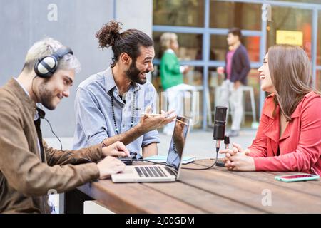 Young man interviewing a woman in a casual radio studio outdoors. Stock Photo