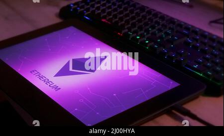 Ethereum on a pad and screen, pink image and presentation of new technology. Stock Photo