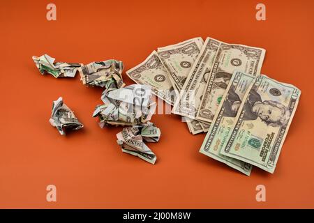 A pile of crumpled and dirty dollar bills lying on an orange table. Dirty money concept. Stock Photo