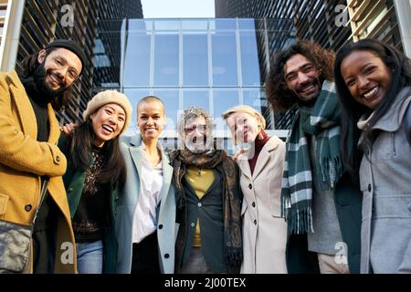 Business team portrait looking at the camera smiling portrait. Man and women outdoors together in group photo with modern office at background Stock Photo