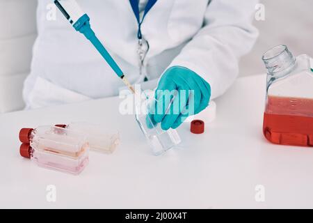 Im going to need a few drops of this.... Cropped shot of an unrecognizable female scientist using a dropper while conducting an experiment in a Stock Photo