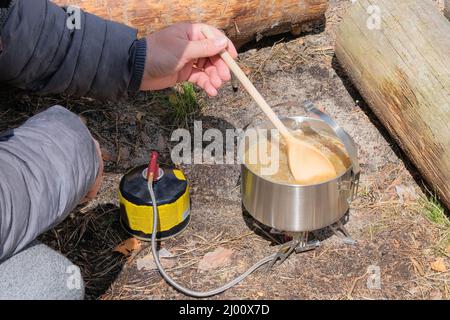 Camping food making. Traveler foods for outdoor activities. Soup in pot in the wild forest. Stock Photo