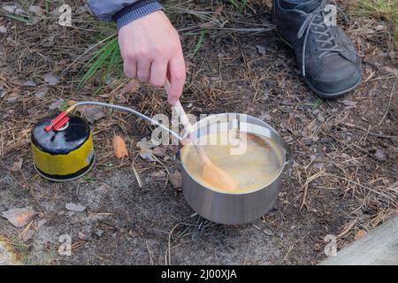 Soup in pot in the wild forest. Camping food making. Traveler foods for outdoor activities. Stock Photo