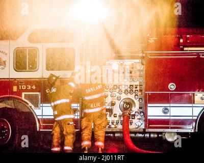 Two Firefighters in action at night with truck and water cannon Stock Photo