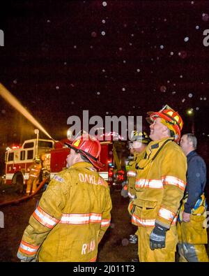 Two Firefighters in action at night with truck and water cannon Stock Photo
