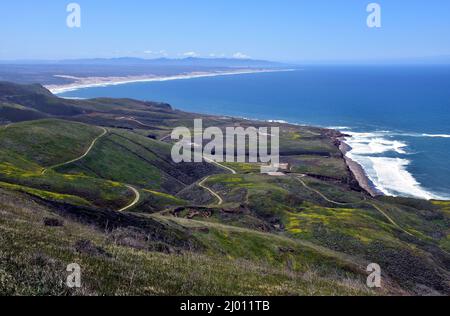 View from Top of a Hill Looking Down on More Hills with Mustard Growing and the Pacific Ocean with Mountains in the Distance Stock Photo