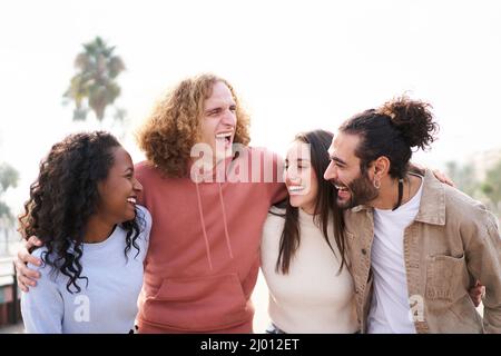 Smiling Friends laughing and having fun together. outdoors. Happy multiethnic young group of people hugging together. Stock Photo