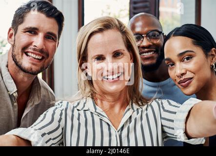The team you need. Cropped portrait of a group of business colleagues taking selfies in the office. Stock Photo