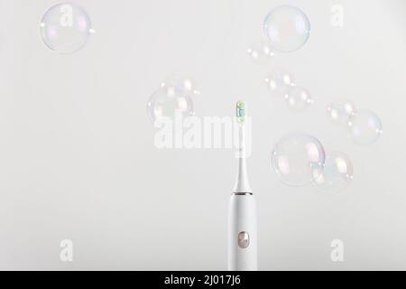 Electronic toothbrush among bubbles on white background. Stock Photo