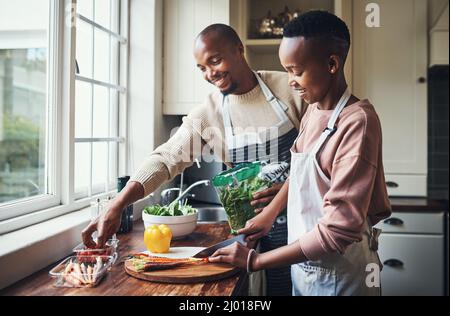 Preparing dinner together. Cropped shot of an affectionate young couple preparing dinner in their kitchen. Stock Photo