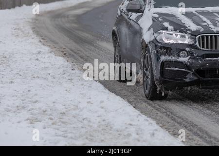 suv drives on partially snowy road Stock Photo