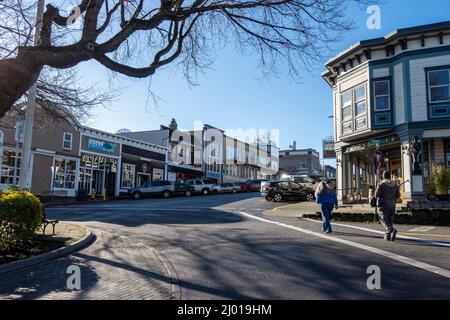 Friday Harbor, WA USA - circa November 2021: View of pedestrians crossing a major intersection in the heart of downtown Friday Harbor on a bright, sun Stock Photo