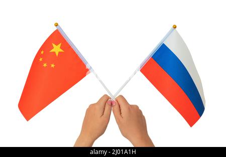 Female hand holding Russian and Chinese flag, isolated on white background Stock Photo