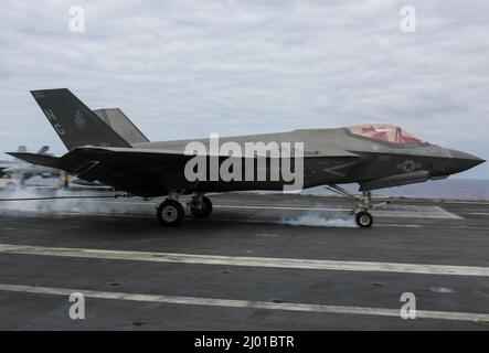 Philippine Sea, United States. 11 March, 2022. A U.S. Marine Corps F-35C Lightning II fighter jet, assigned to the Black Knights of Marine Fighter Attack Squadron 314, makes an arrested landing on the flight deck of the Nimitz-class aircraft carrier USS Abraham Lincoln during routine operations, March 11, 2022 in the Philippine Sea.  Credit: MCS Aleksandr Freutel/Planetpix/Alamy Live News Stock Photo