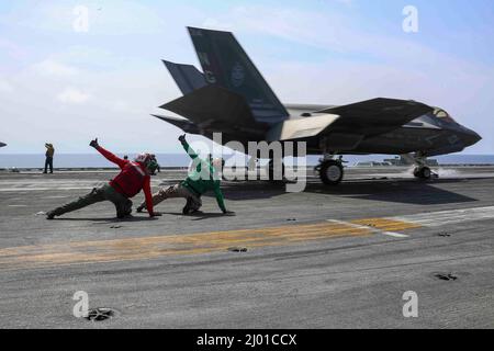 PHILIPPINE SEA (March 15, 2022) Sailors signal an F-35C Lightning II, assigned to the 'Black Knights' of Marine Fighter Attack Squadron (VMFA) 314, as it launches from the flight deck of the Nimitz-class aircraft carrier USS Abraham Lincoln (CVN 72) to conduct a joint longe-range air demonstration in the Yellow Sea, March 15. Abraham Lincoln Strike Group is on a scheduled deployment in the U.S. 7th Fleet area of operations to enhance interoperability through alliances and partnerships while serving as a ready-response force in support of a free and open Indo-Pacific region. (U.S. Navy photo by Stock Photo
