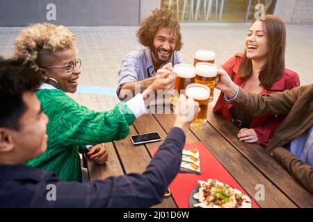 Group of happy people toasting and having lunch in a terrace. Focus is on man. Stock Photo