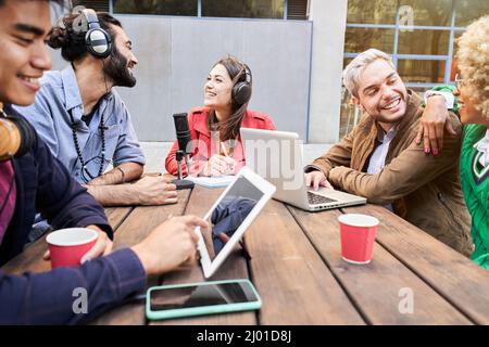 Woman interviewed a man for a podcast outdoors. Young people streaming with casual studio broadcasting. Stock Photo