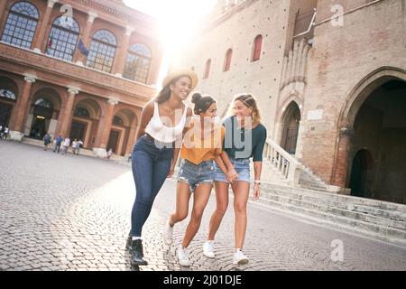 Three mixed race female friends having fun at the city in summer vacations. Women laughing together outdoors Stock Photo