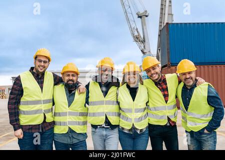 Multiracial worker people having fun inside container cargo terminal at maritime port - Main focus on indian man face Stock Photo
