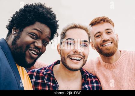 Diverse friends having fun together doing selfie outdoor - Focus on gay male face wearing makeup Stock Photo
