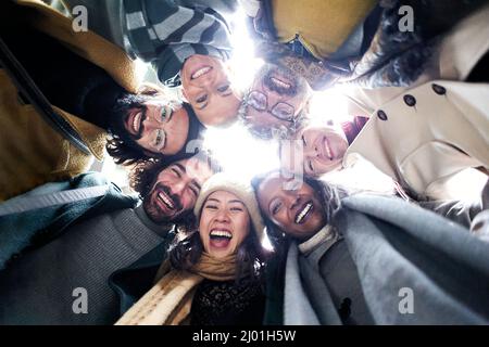 Low angle circle of a cheerful diverse group of people of diverse races an aged looking at camera happy together having fun Stock Photo