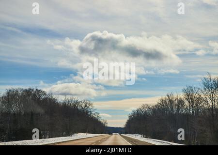 Winter drive open road with fluffy clouds and blue sky Stock Photo