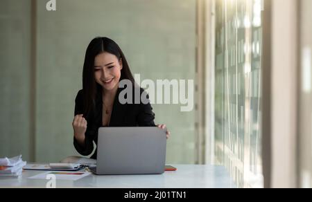 Excited asian female feeling euphoric celebrating online win success achievement result, young woman happy about good email news, motivated by great Stock Photo