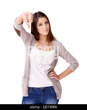 Boo. Smiling young woman giving a thumbs down against a white background. Stock Photo