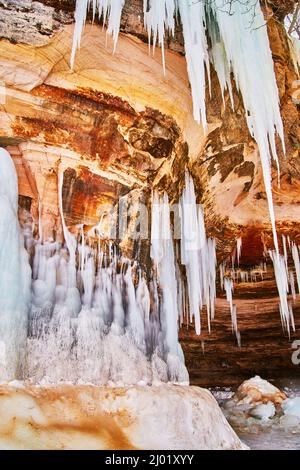 Rock wall with icicles and frozen ice formations in winter Stock Photo