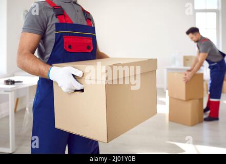 Close up of cardboard box in hands of male employee of moving and delivery company. Stock Photo