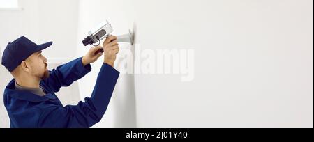 Banner of technician install camera on wall Stock Photo