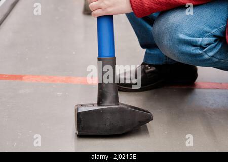 Woman in a building materials store chooses huge, heavy hammer to buy. Close up Stock Photo