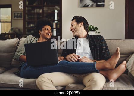 Theres no one else Id rather spend my day with. Full length shot of a happy young couple using a laptop while relaxing on a couch home. Stock Photo