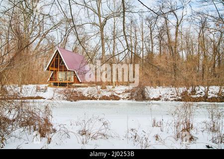 Lone cabin on frozen river in winter with snow Stock Photo