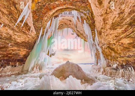 Large ice cave entrance covered in blue and green icicles and broken ice Stock Photo