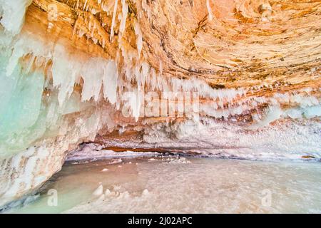 Entrance to magical ice cavern covered in small crystal icicles Stock Photo