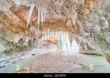 Crystal ice cavern on frozen lake covered in icicles Stock Photo