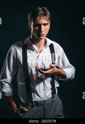 Man holds glass brandy. Young man drink cognac. Man holding a glass of whisky. Stock Photo