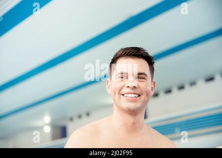 Portrait young man smiling on background of pool, concept of swimmer before training at school. Stock Photo
