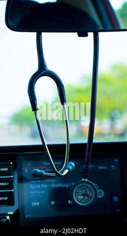 An editorial picture of a Litman stethoscope hanging on a rare view mirror of a doctor's car Stock Photo