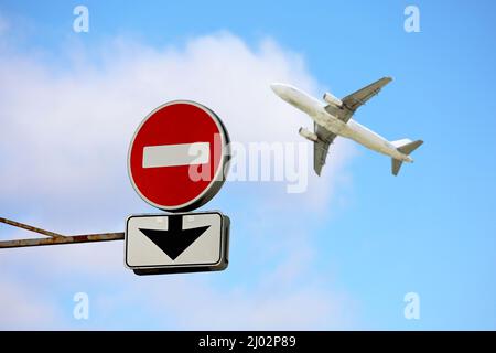 Stop sign with down arrow and airplane in blue sky. Concept of band on flights over Europe from Russia, sanctions due to russian operation in Ukraine Stock Photo