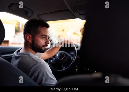handsome bearded young man driving sitting behind the wheel of his car, leisure and driving concept Stock Photo