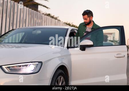 handsome young man with beard gets into his car, leisure and diving concept Stock Photo
