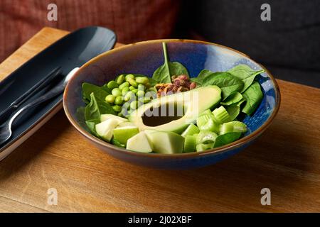 green bowl of healthy food, vegan bowl with avocado, apple and green vegetables on a wooden background Stock Photo