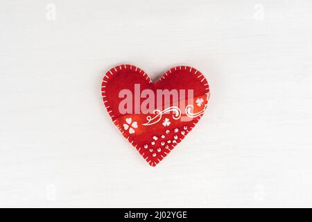 Top view Valentine's Day concept with copy space. Red textile heart on white wooden background