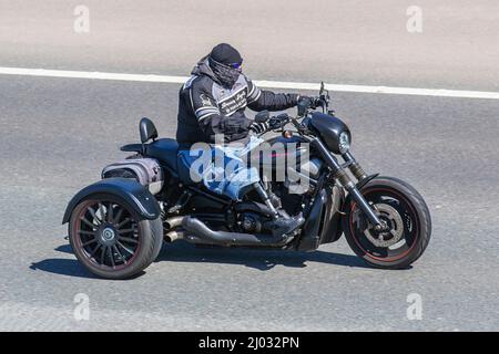 Disabled motorcyclist wearing a prosthesis an artificial replacement for a missing limb enjoys a ride out on his Harley-Davidson Trike in bright sunny conditions on the M6 motorway. Stock Photo