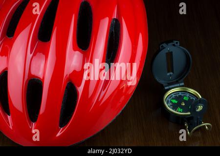 Red cycle helmet with compass on a polished wooden table top Stock Photo