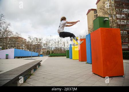 series of photos of young man jumping practicing parkour in the street jumping between color blocks Stock Photo